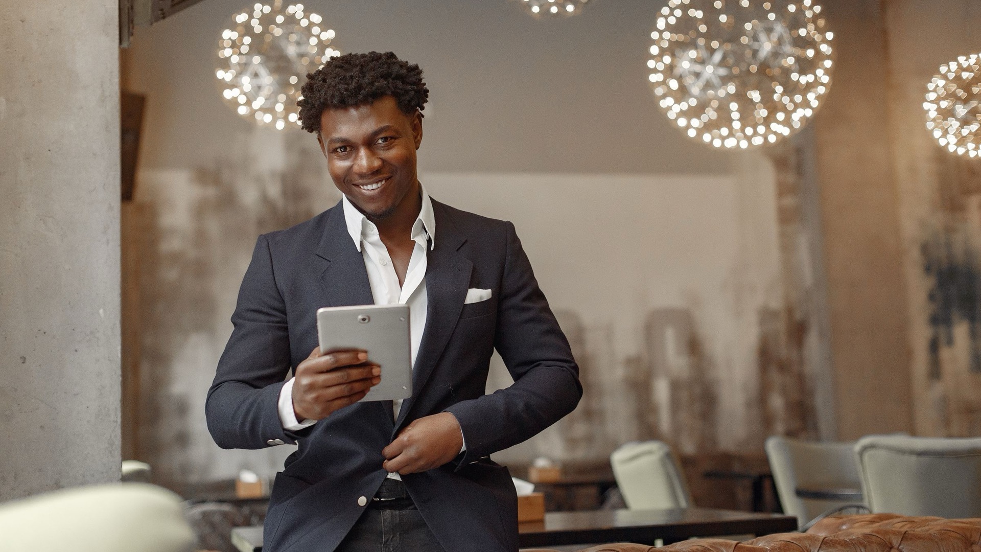 A restaurant owner smiling with a tablet in his dining room, part of a restaurant digital transformation